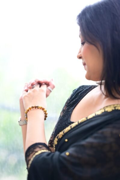 Elegant woman in a black saree wearing a Tiger Eye crystal bracelet, symbolizing confidence and inner strength.
